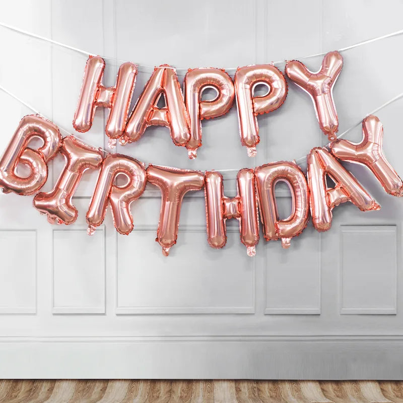 A banner made of pink foil letter balloons spelling out HAPPY BIRTHDAY hanging on a white door.