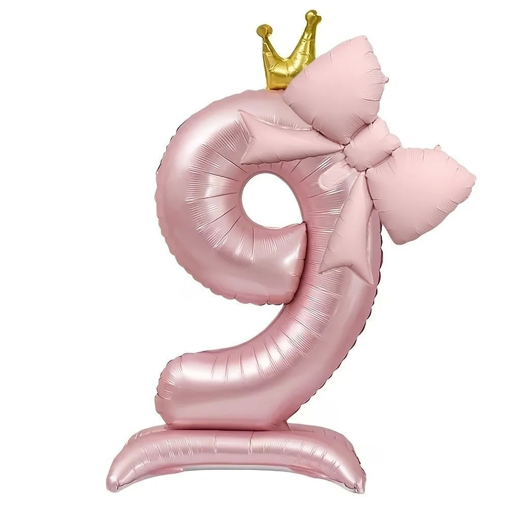 A pink foil balloon shaped like the number 9 with a gold crown topper.