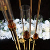 Elegant gold metal candle holders displayed with white flowers on a dark surface.