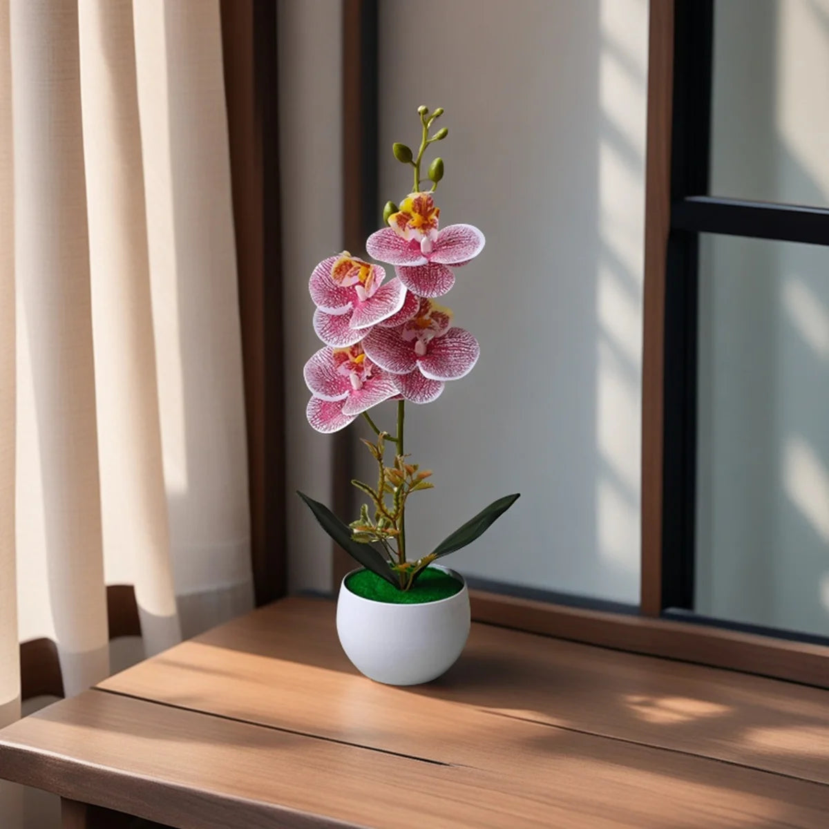 A realistic artificial orchid with pink flowers is potted in a white ceramic pot on a wooden surface.