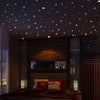 A bedroom scene with a bed and dark wood paneling decorated with glow-in-the-dark star wall stickers on the ceiling.