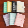 A set of five 100 envelope savings challenge binders in various colors including green, yellow, black, beige, and pink.