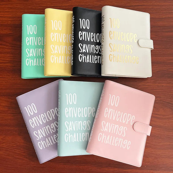 A set of five 100 envelope savings challenge binders in various colors including green, yellow, black, beige, and pink.