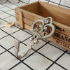 A pair of vintage silver crown curtain hooks resting on a wooden box with engraved text.