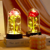 A glass dome display featuring a preserved pink rose with glowing stems on a dark base.