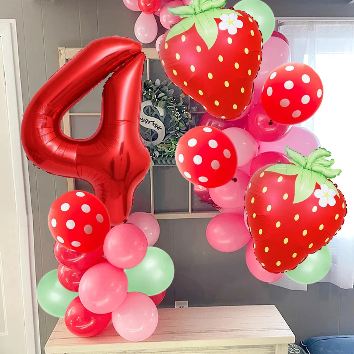 A collection of red and pink strawberry foil balloons in various sizes and shades