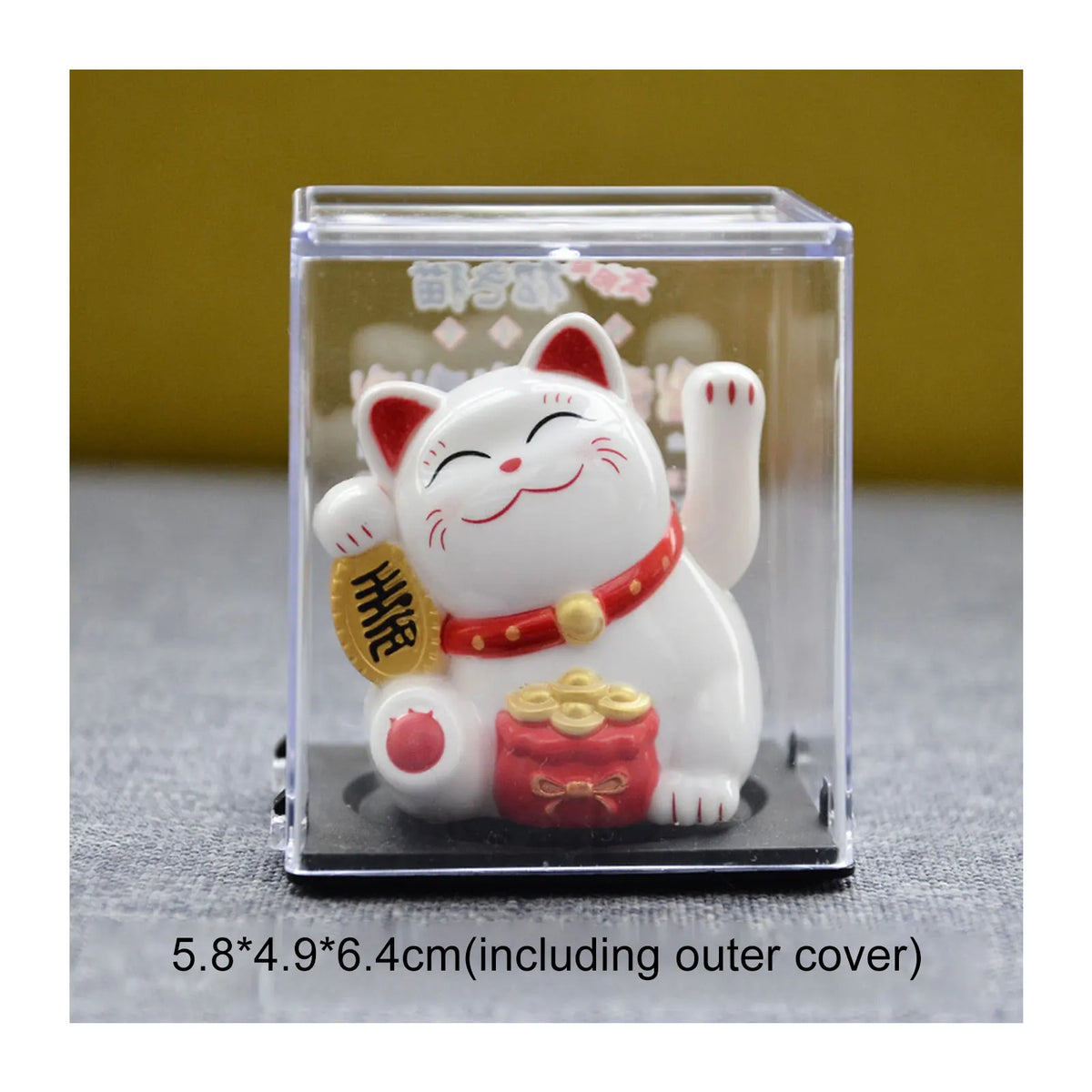 A white ceramic figurine of a cat with red accents is displayed inside a clear box.