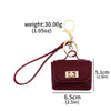 A maroon mini leather openable bag with a gold chain keychain attached.