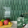 A display of fresh fruits on a yellow tray set against a background of green subway tiles.