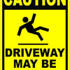 A yellow caution sign with black text warning that the driveway may be icy.