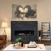 A tapestry featuring a close-up portrait of two women embracing, displayed above a modern fireplace and wooden shelving.