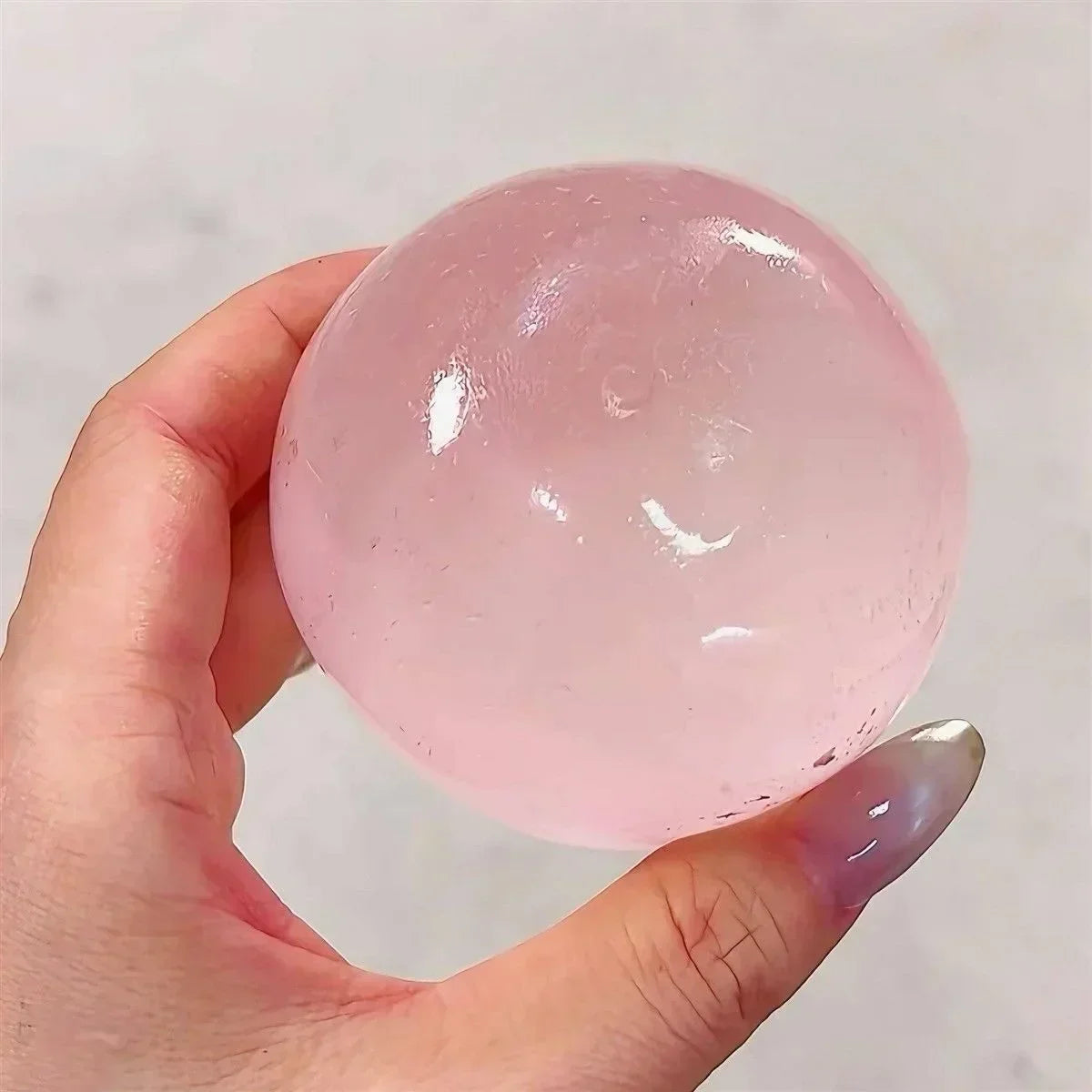 A hand holds a clear pink squishy toy shaped like a cat paw, showing its smooth surface.