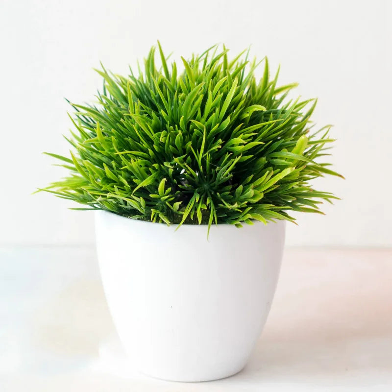 Un vibrant bonzai artificiel vert dans un pot blanc repose sur une surface claire.