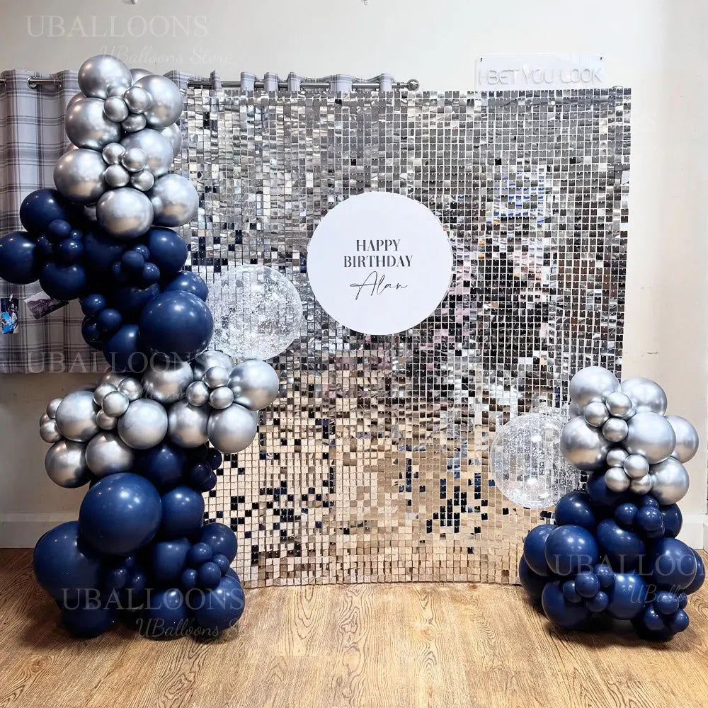 A balloon garland featuring metallic gold and navy blue balloons against a sparkling silver background.