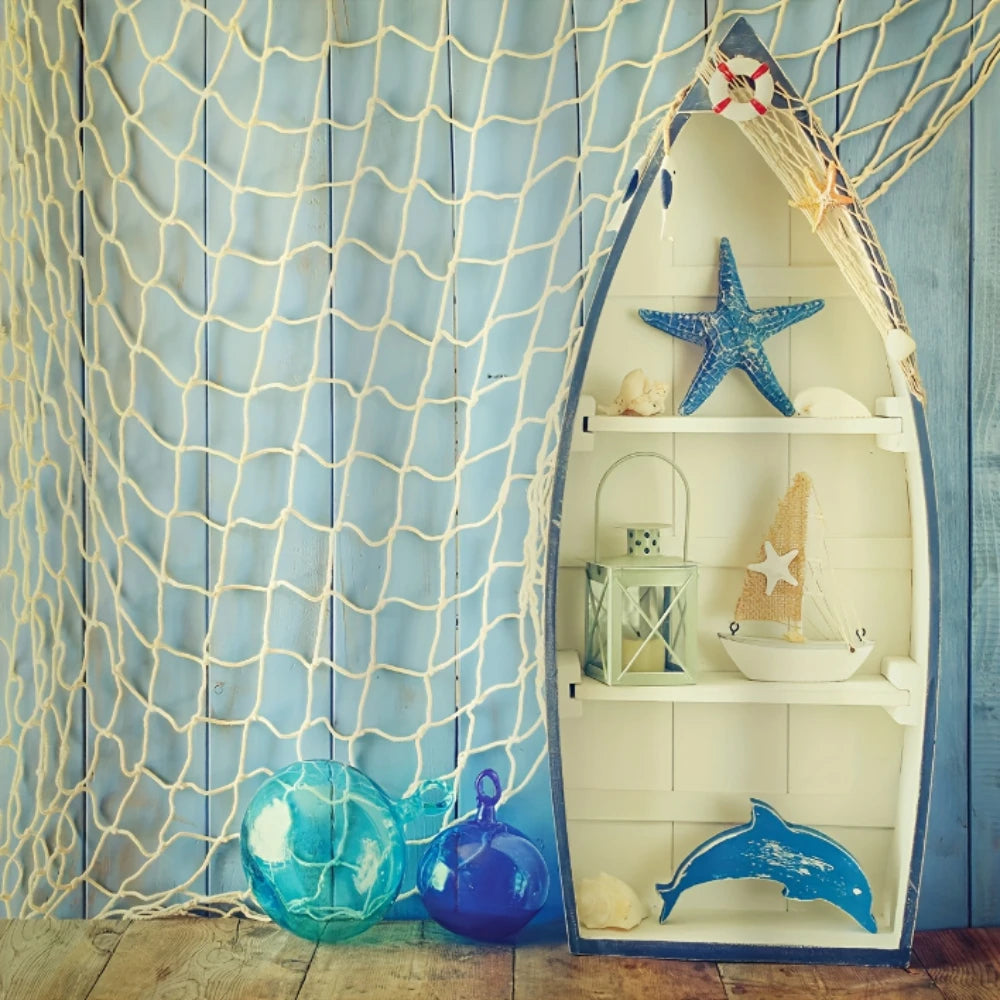 Malla de pez decorativa blanca con adornos de vidrio azul y estrellas de mar sobre fondo de madera azul claro.