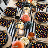 A table set with black and orange Halloween themed paper napkins, pumpkins, and metallic accents.