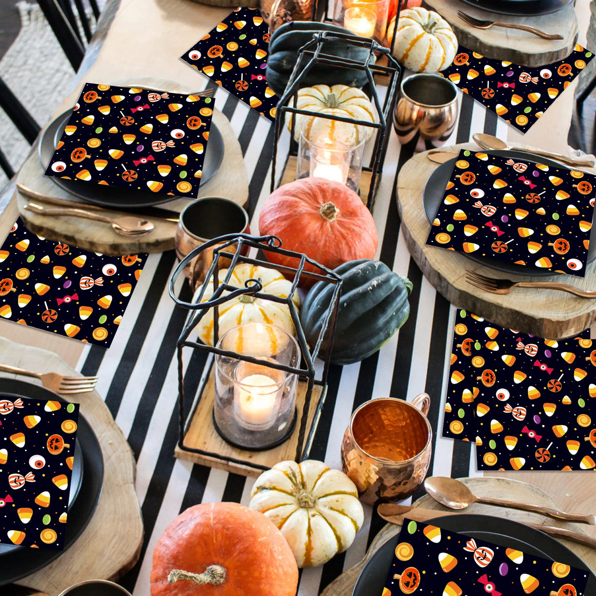 A table set with black and orange Halloween themed paper napkins, pumpkins, and metallic accents.