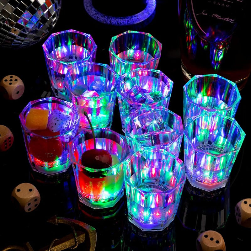 A collection of glowing LED light-up shot glasses arranged on a dark surface.
