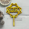 A gold acrylic birthday cake topper shaped like a hexagon with the words Happy Birthday on a stick.