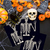 Halloween skeleton and spider design on dark paper napkins surrounded by autumn leaves and pumpkins