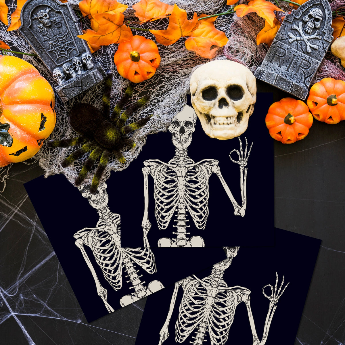 Halloween skeleton and spider design on dark paper napkins surrounded by autumn leaves and pumpkins