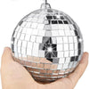 A silver disco mirror ball sphere with a hanging mechanism is held in a hand.