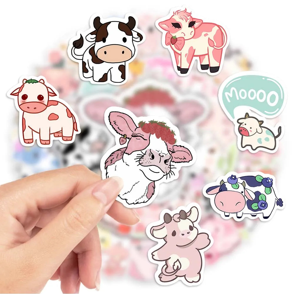 A hand is holding several cute pink cow cartoon decals for DIY decoration on a light background.