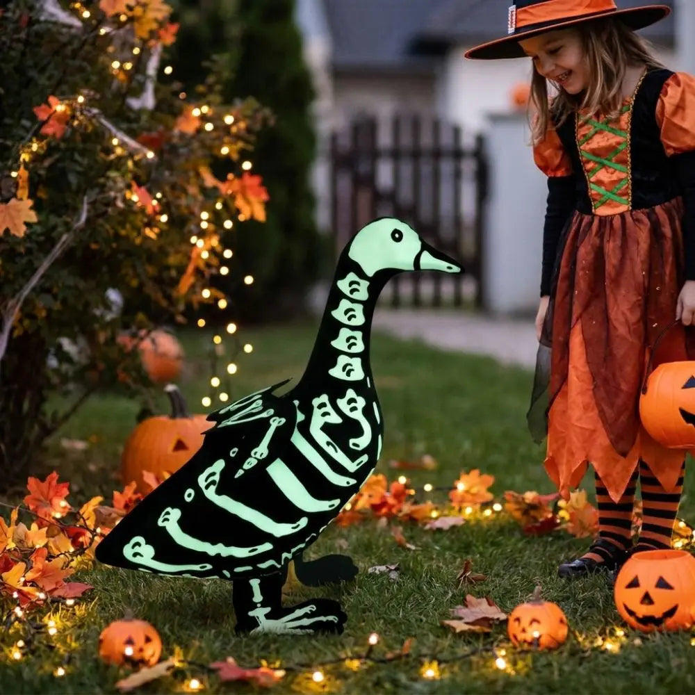 A luminous skeleton goose lawn decor is placed on green grass surrounded by autumn leaves and string lights.