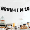 A black felt banner spelling out Bruh I'm 10 for a birthday party decoration setup.