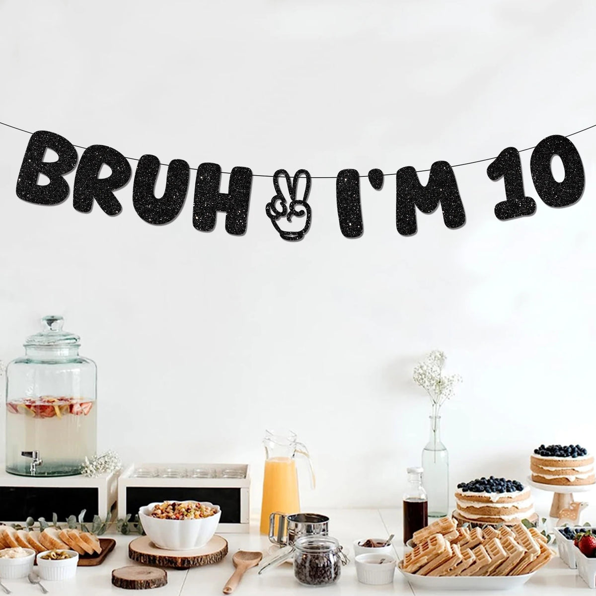 A black felt banner spelling out Bruh I'm 10 for a birthday party decoration setup.