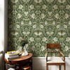 Gros plan d'une pièce avec papier peint floral bohème autocollant sur un mur, à côté d'une chaise en bois et d'une petite tab