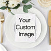 A white greeting card with the text Your Custom Image placed on a stack of white plates with gold cutlery and greenery.