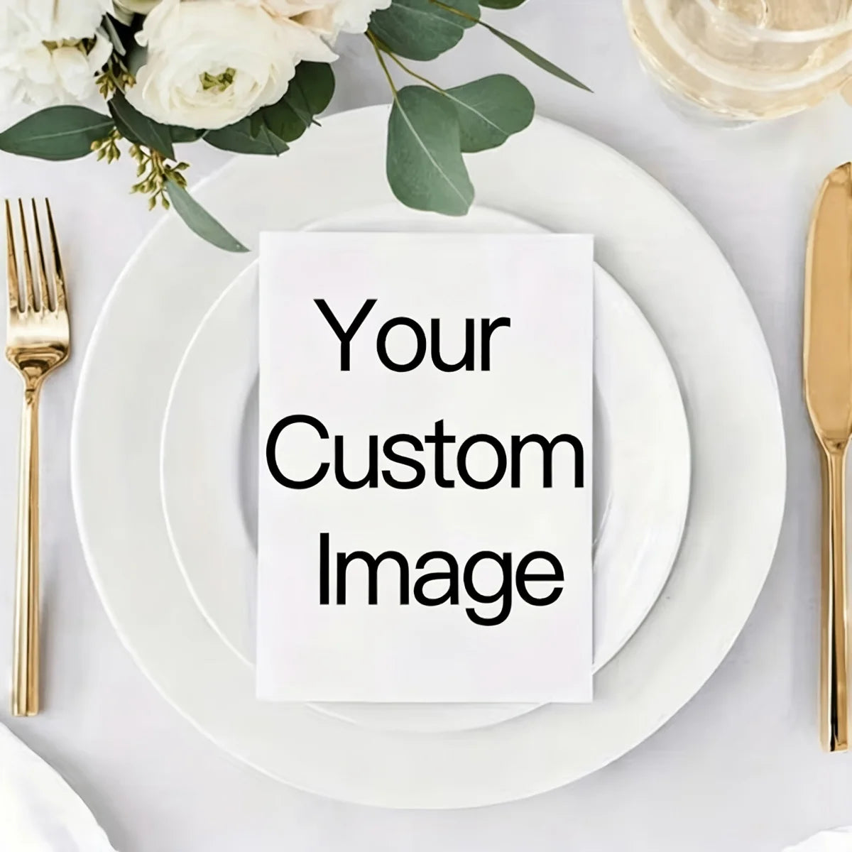 A white greeting card with the text Your Custom Image placed on a stack of white plates with gold cutlery and greenery.