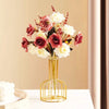 A golden iron hollow vase holds a bouquet of pink and white roses and foliage.