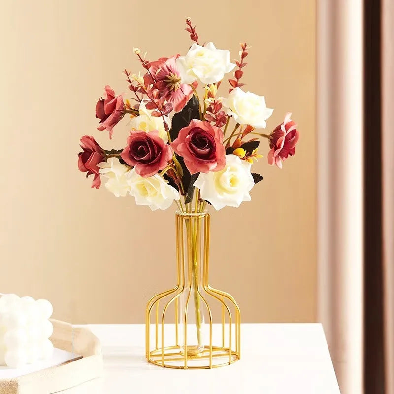 A golden iron hollow vase holds a bouquet of pink and white roses and foliage.