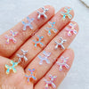 Hand displaying various clear and iridescent balloon puppy nail art charms