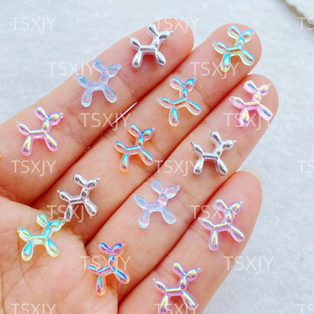 Hand displaying various clear and iridescent balloon puppy nail art charms