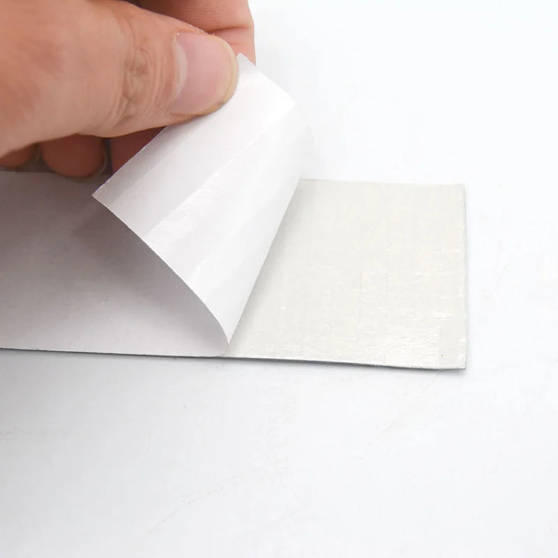 A hand is holding a white 3D mirror mosaic wall tile, showing its thickness and texture.
