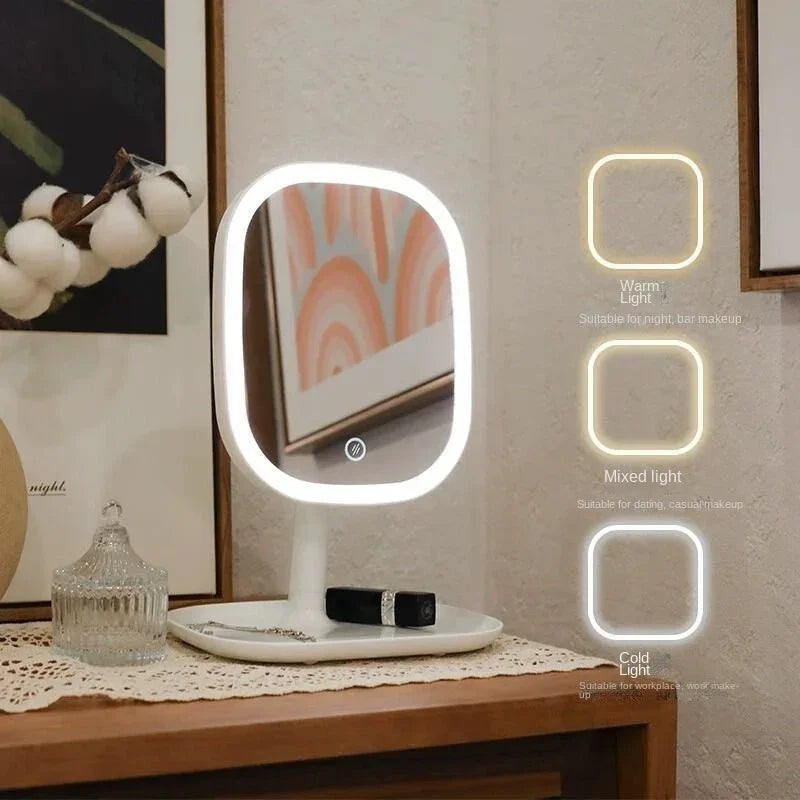 A white vanity mirror with three illuminated light settings: warm, mixed, and cold light, displayed on a wooden surface.