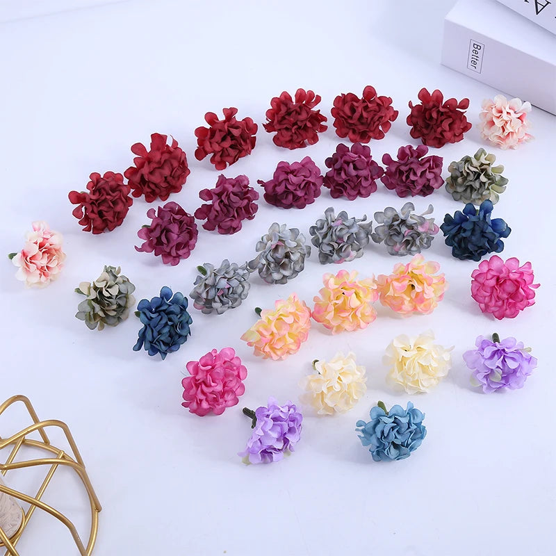 Collection de petites fleurs d'hydrangea artificielles dans diverses nuances de rouge, rose, violet et vert.