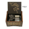 A dark wooden box containing a music melody box with a character design on the lid.