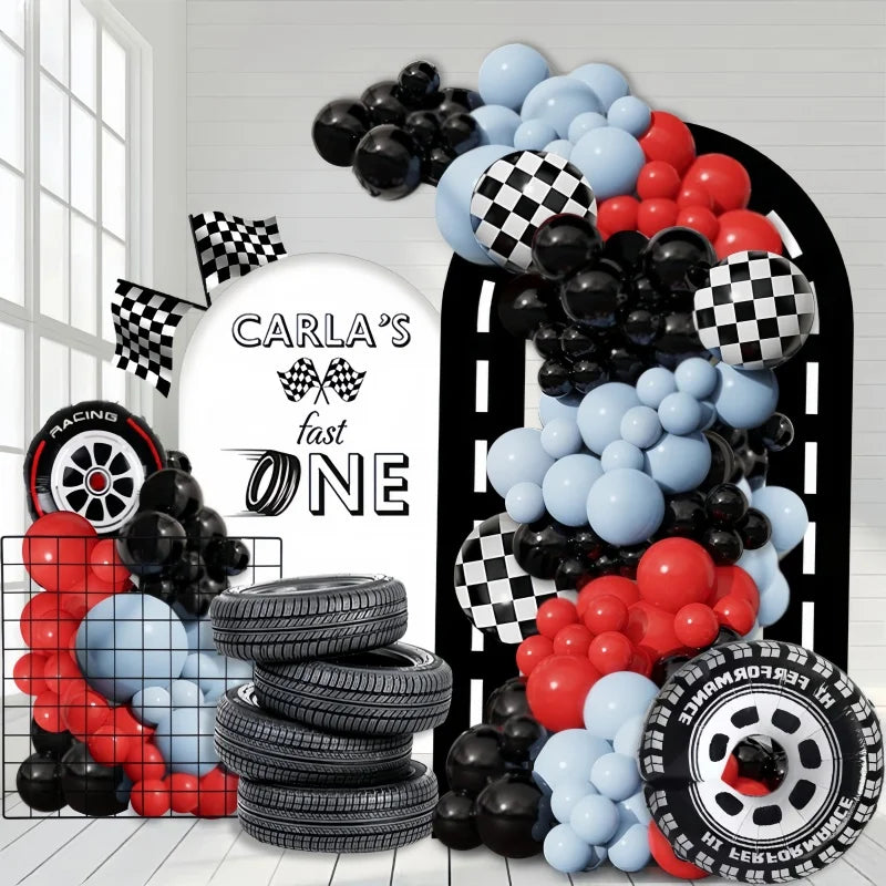 A balloon arch set featuring black and red balloons and stacked tires with a racing theme.