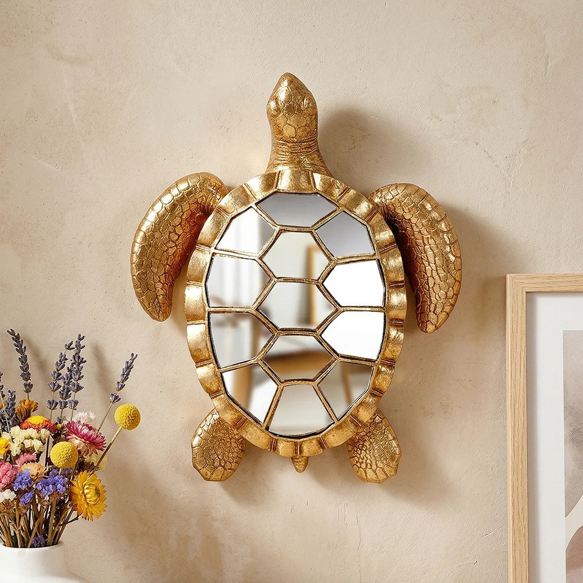 Golden sea turtle resin wall decor mirror with a textured frame mounted on a beige wall.