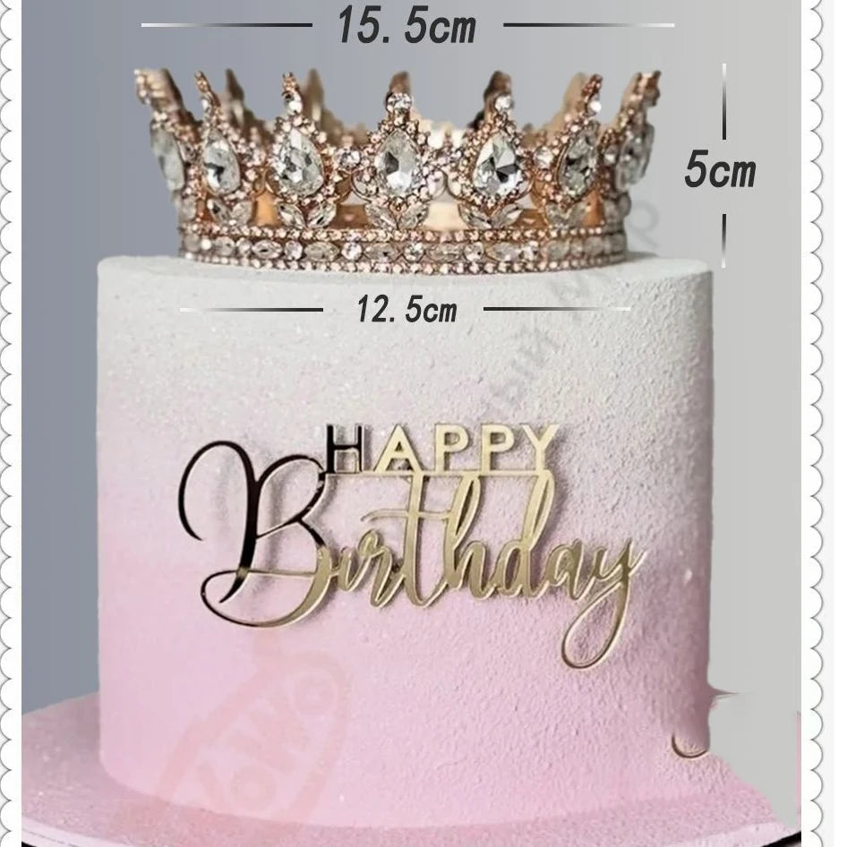 A pink buttercream cake decorated with a crystal rhinestone crown topper and gold lettering that reads Happy Birthday
