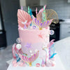 A pink mermaid cake decorated with colorful edible toppers of shells, seaweed, and starfish.