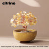 Handcrafted crystal tree with natural yellow crystals mounted on a copper wire base in a light bowl.