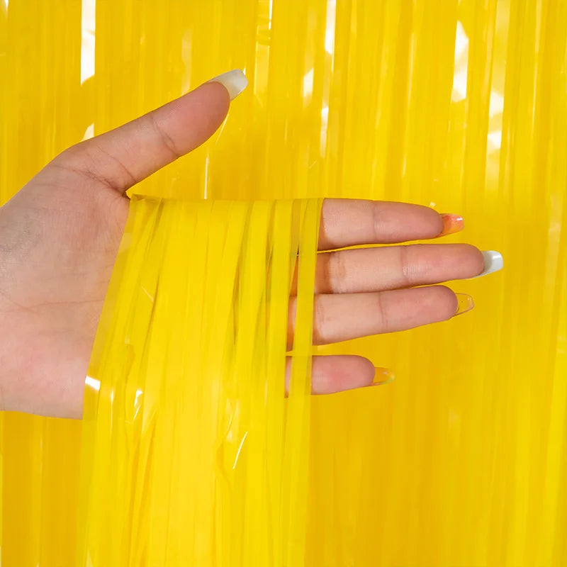 Hand holding bright yellow metallic tinsel foil fringe curtain backdrop