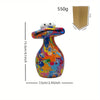 A colorful resin figurine of a frog with large eyes, displayed next to its packaging.