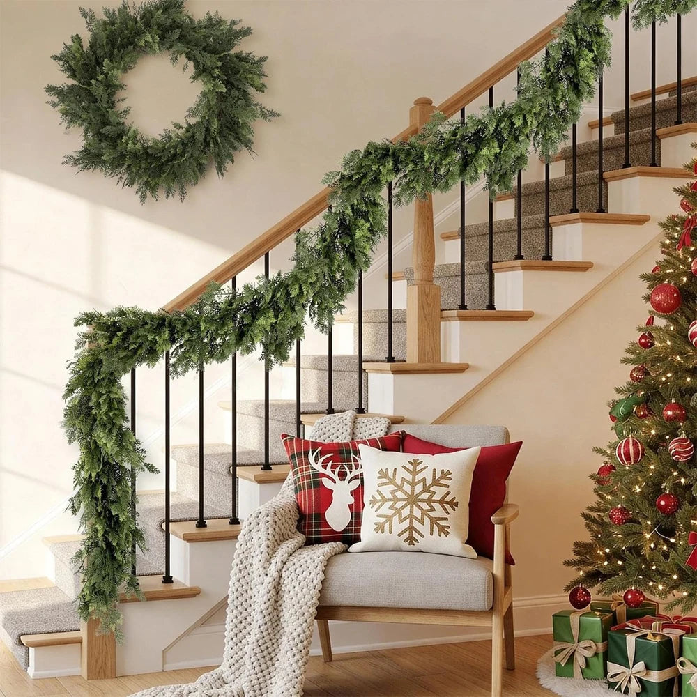 An artificial cedar garland draped along a wooden staircase railing in a bright interior setting.
