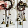 A set of rustic metal decorative door and window handles featuring dark wood wreaths and brass bells.